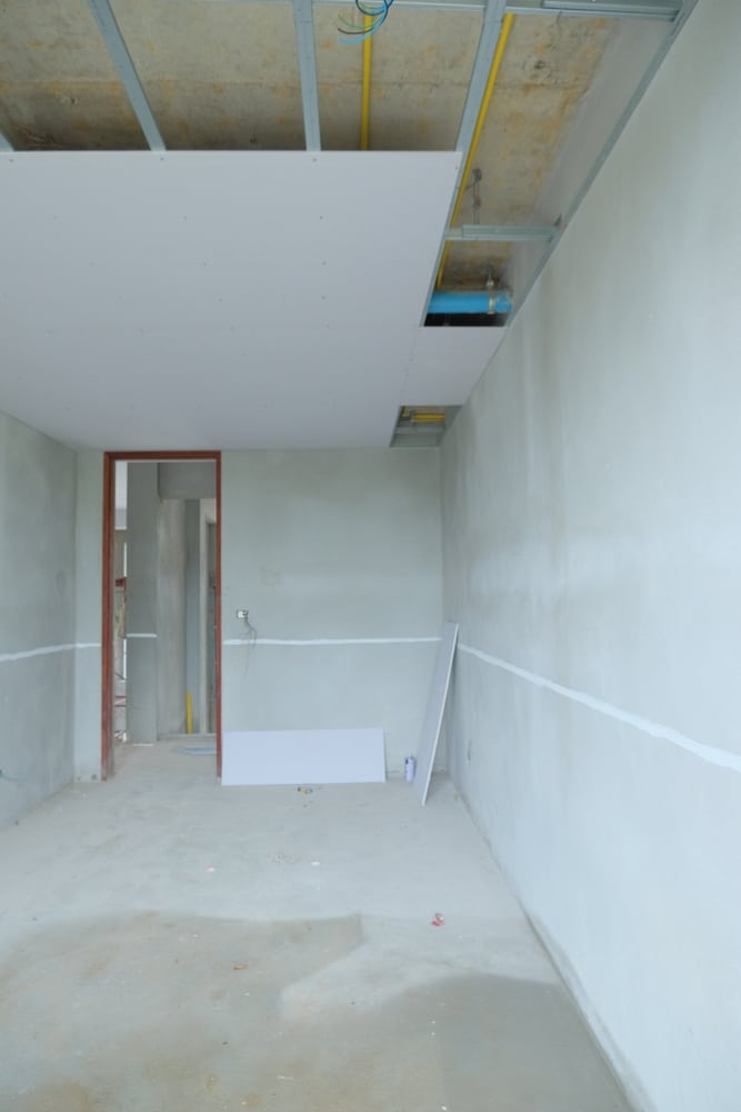 Pose de Plafond en Plaques de Plâtre : Chantier Intérieur Pose de plaques de plâtre au plafond lors d'une rénovation intérieure avec gaines techniques visibles.